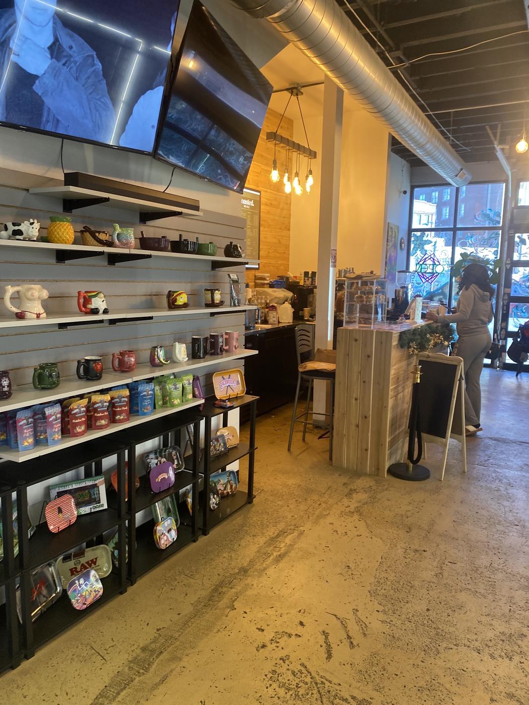 Inside the shop: shelves of novelty ceramic mugs and rolling trays, with the coffee counter beyond.