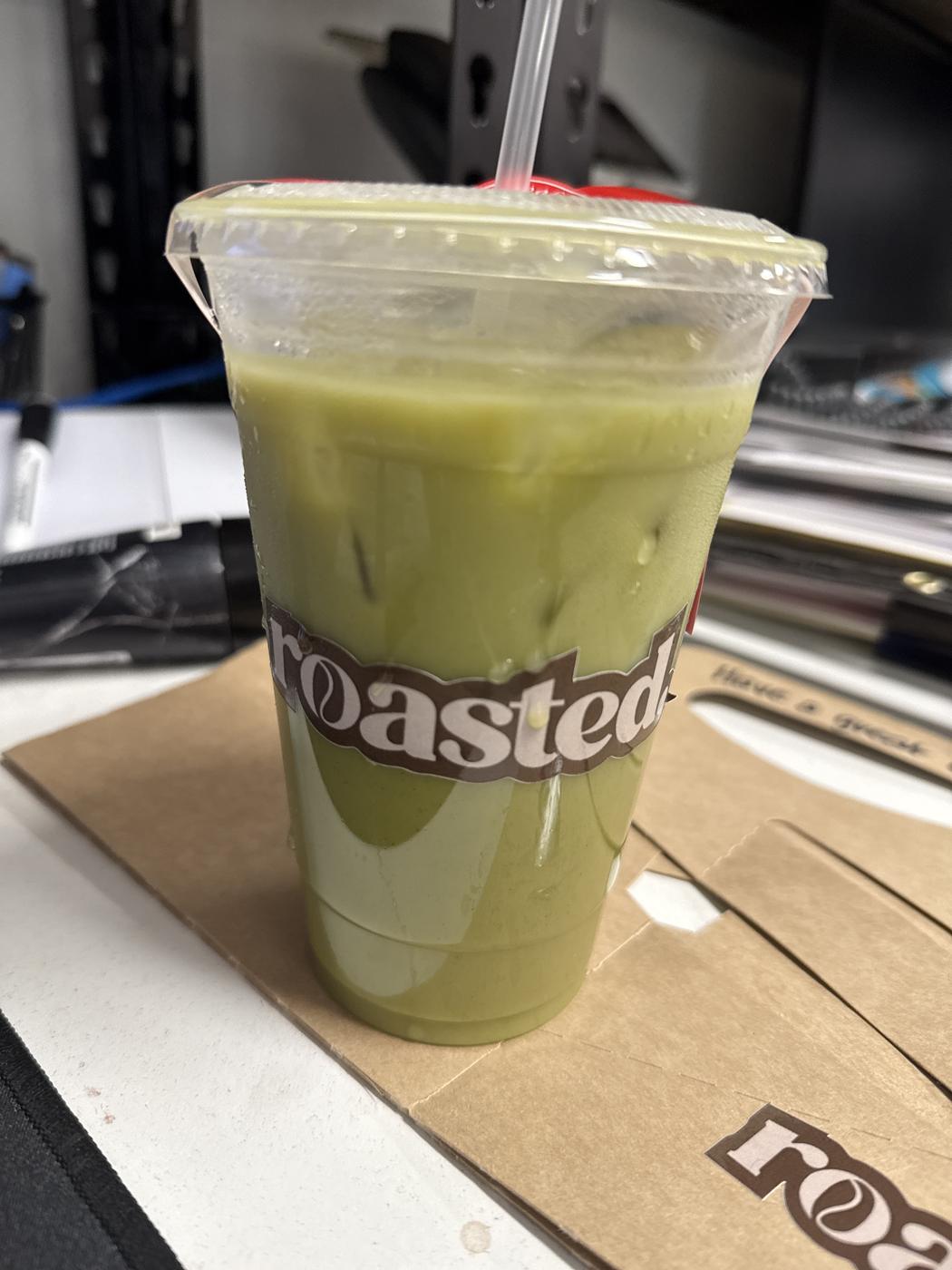 An iced matcha in a roasted. branded cup.
